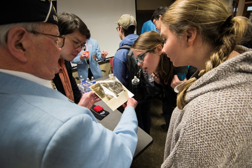Roger Hill, Rochester KWVA chapter commander, shows a photo of captured North Korean soldiers to professor Daphon Ho and students Maureen Lamont '16, and Christina Rutherford '16.