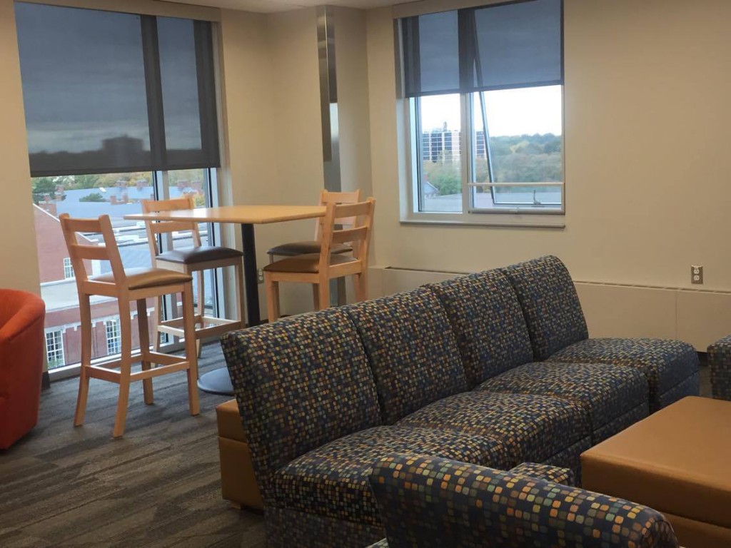 Lounge with couch, bar table and chairs, windows with a view of campus