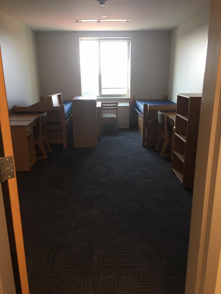 Shot of a dorm room from the door, containing lots of floor space