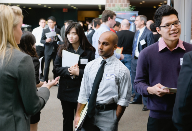 Two students speak with a potential employer