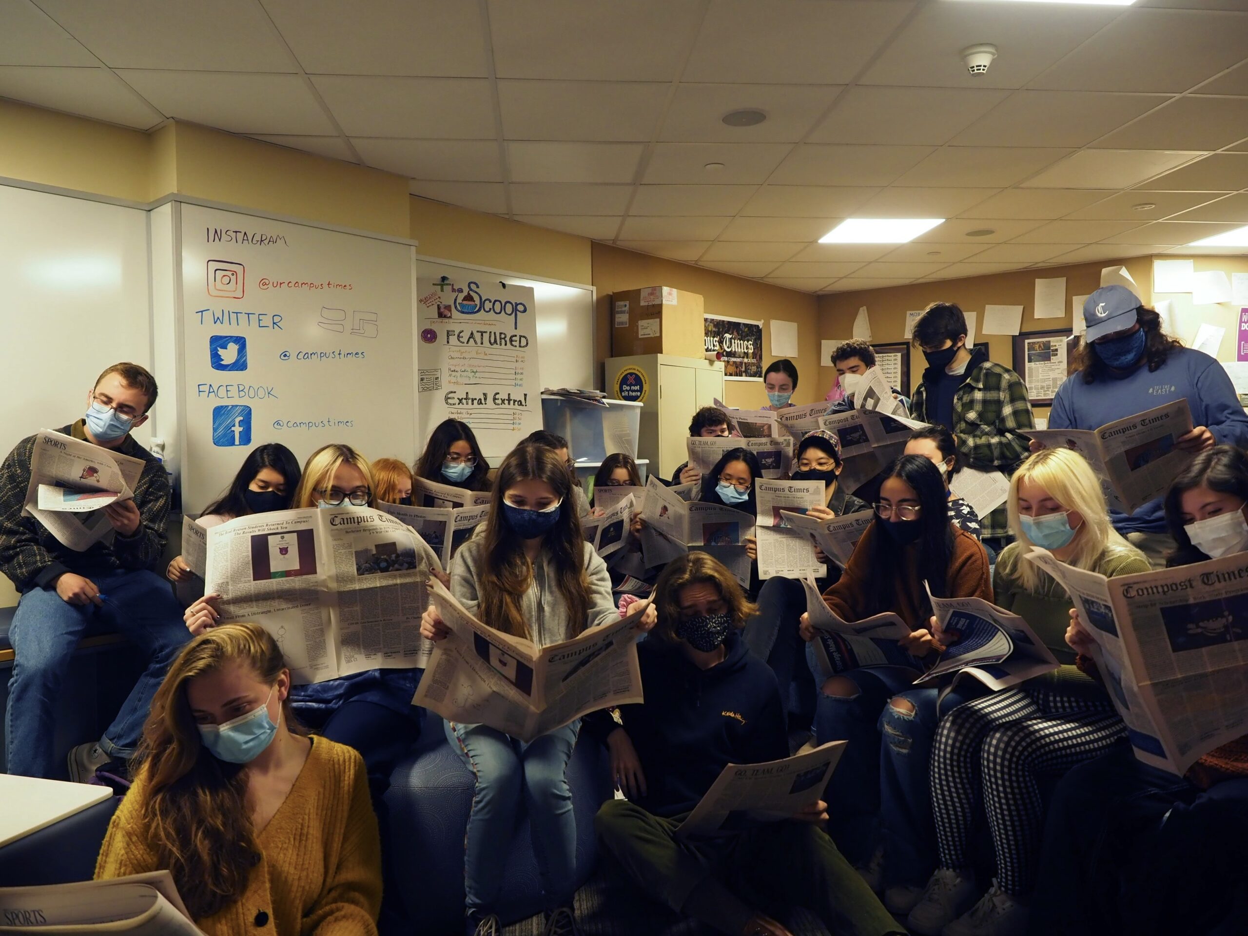 Group of masked CT staff reading the paper.