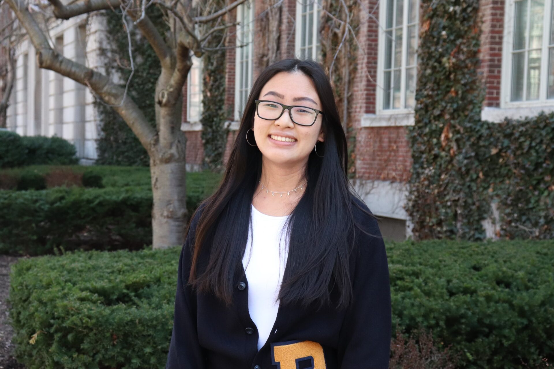 Sarah Lee stands in front of a brick building on Eastman Quad