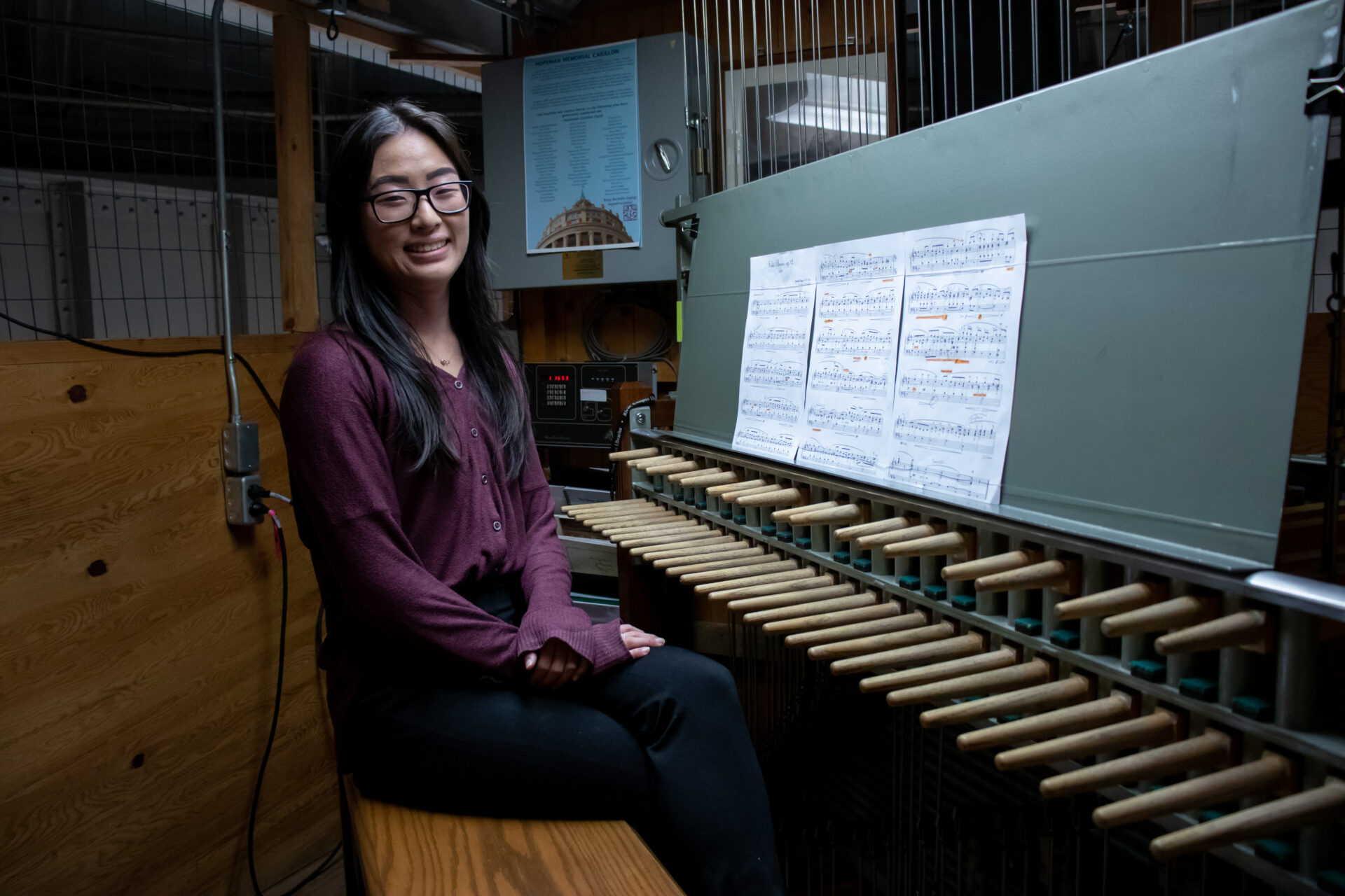 Sarah Lee sits on the bench next to an array of wooden batons that are the carillon keys.