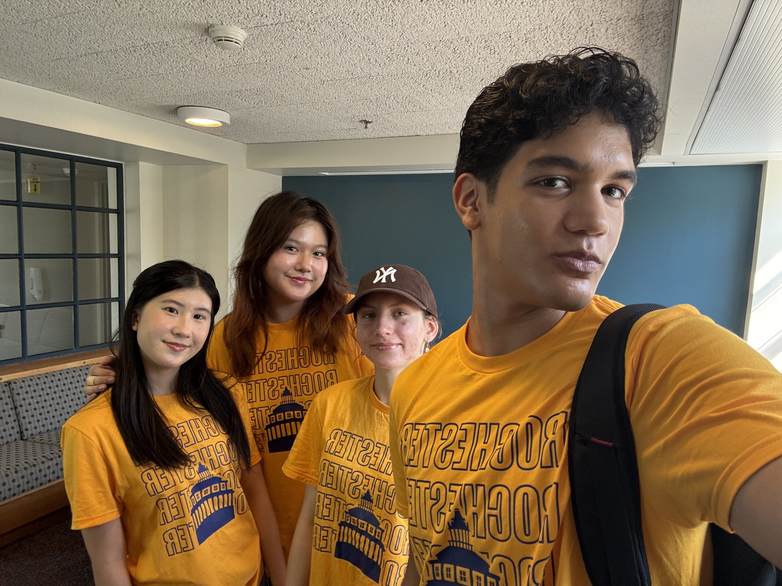 Four URochester student pose for a selfie in yellow Welcome Week t-shirts.