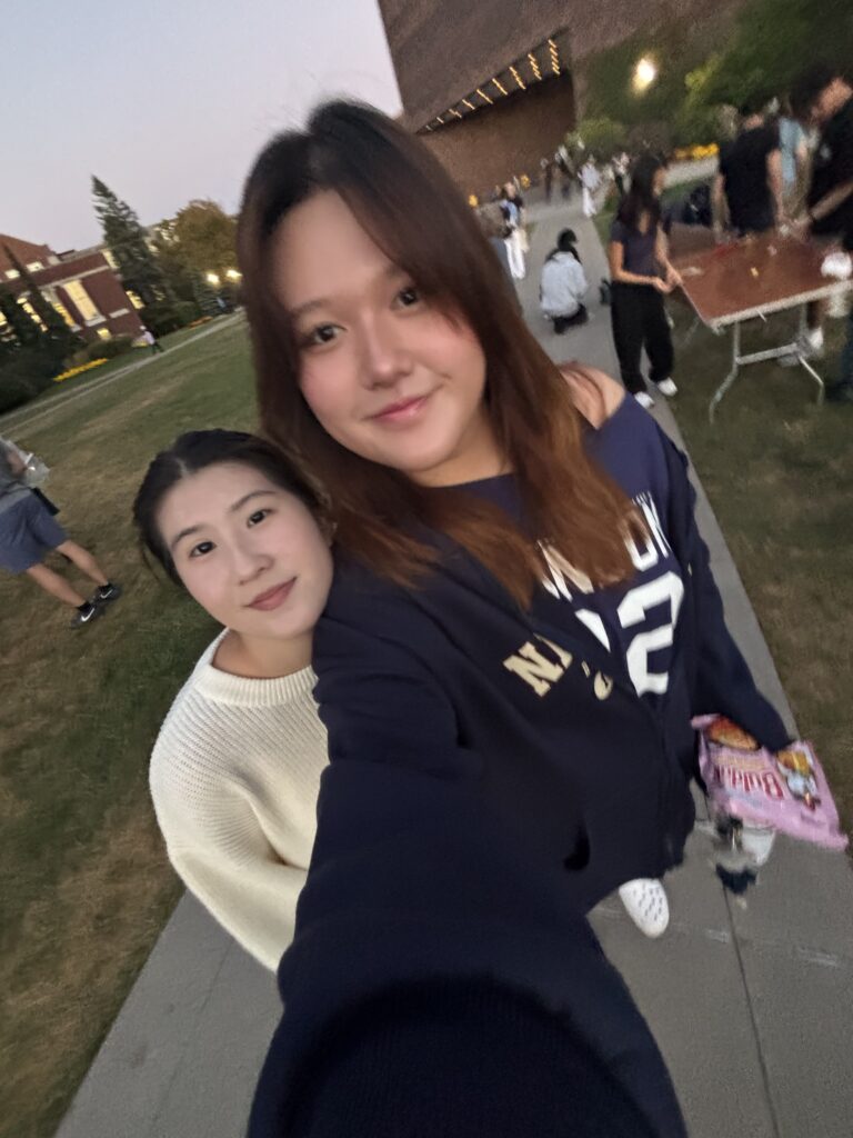 Two students pose for a selfie while walking the path on Wilson Quad.