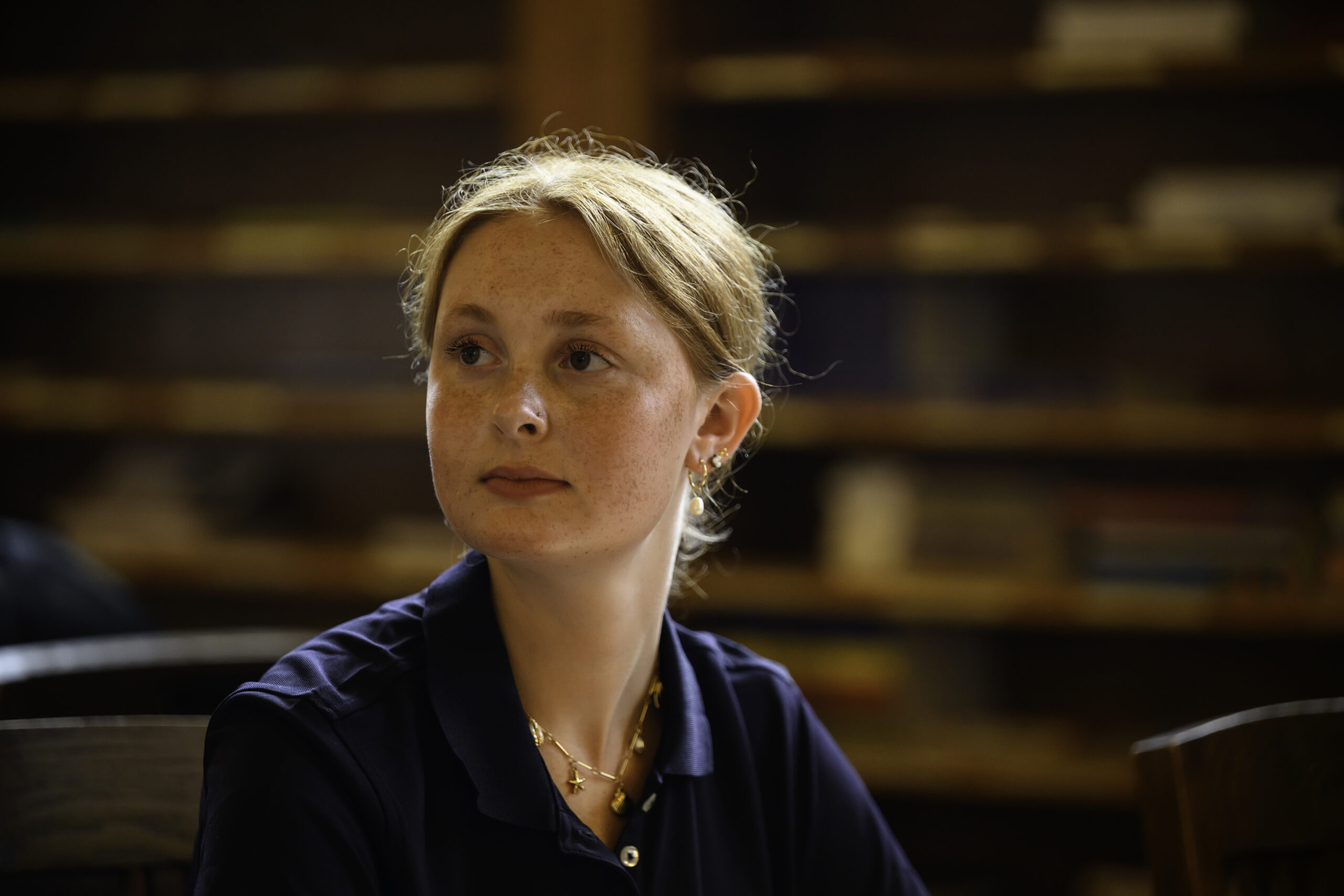 A student in a navy URochester polo studies in the Periodical Reading Room at URochester.