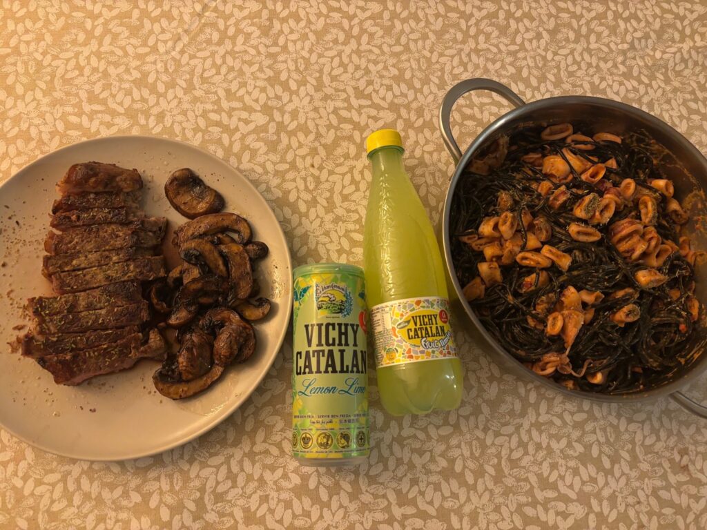 A steak and mushroom dinner, some drinks from Catalonia, and a pasta dish in a pan. 