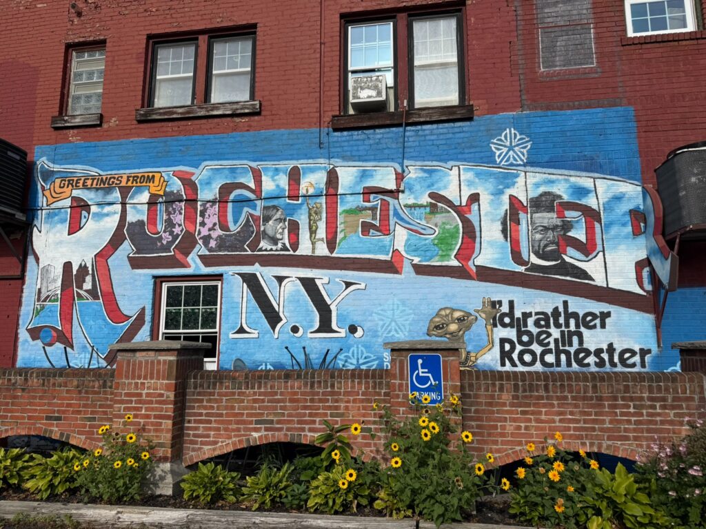 A mural of Rochester, NY with many city symbols and ET with text reading "I'd rather be in Rochester."