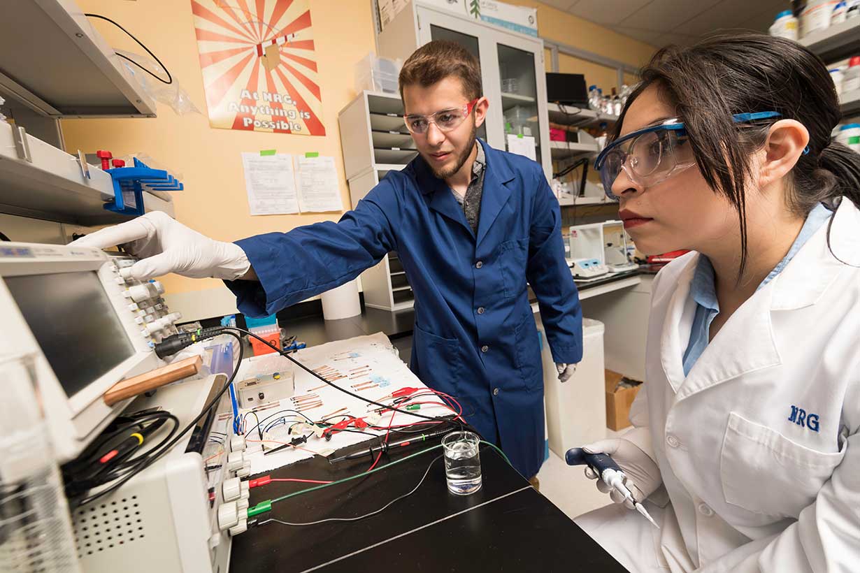 Two students in lab coats working together.