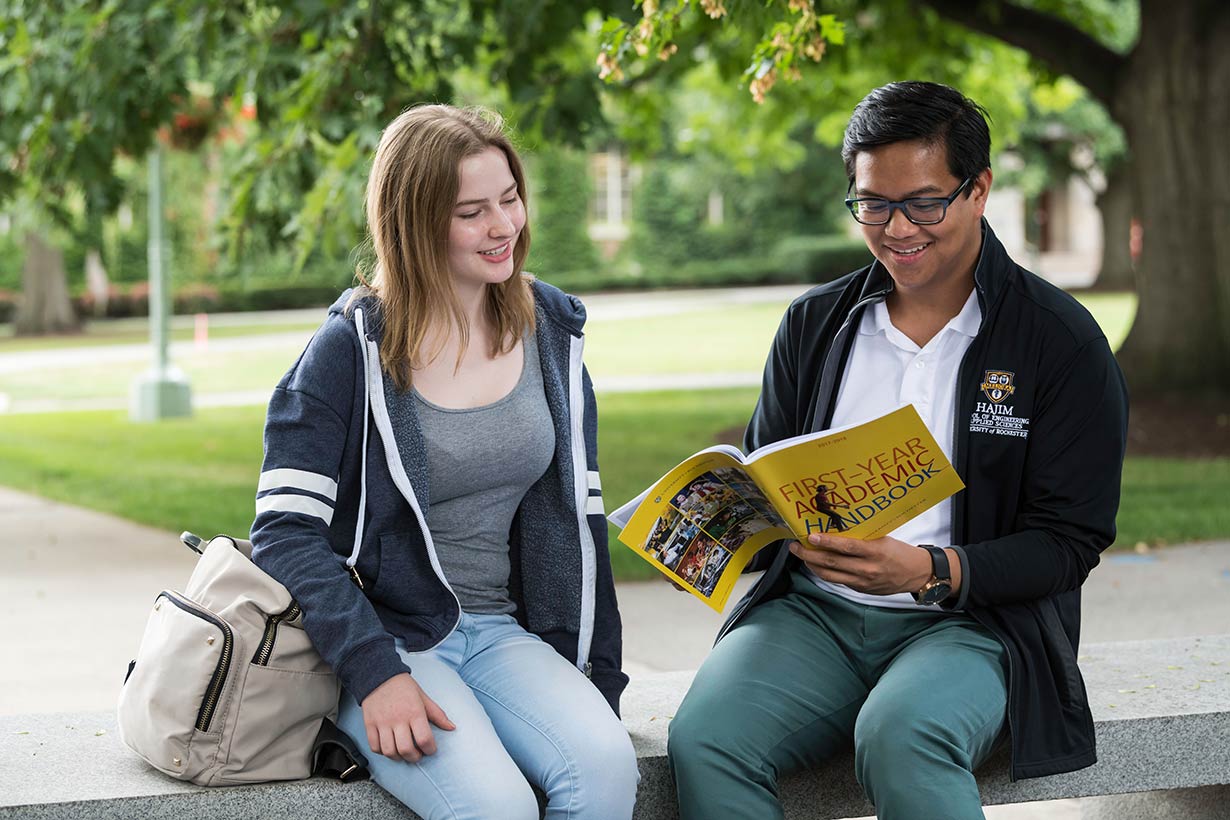 A student looking through a handbook with an advisor.