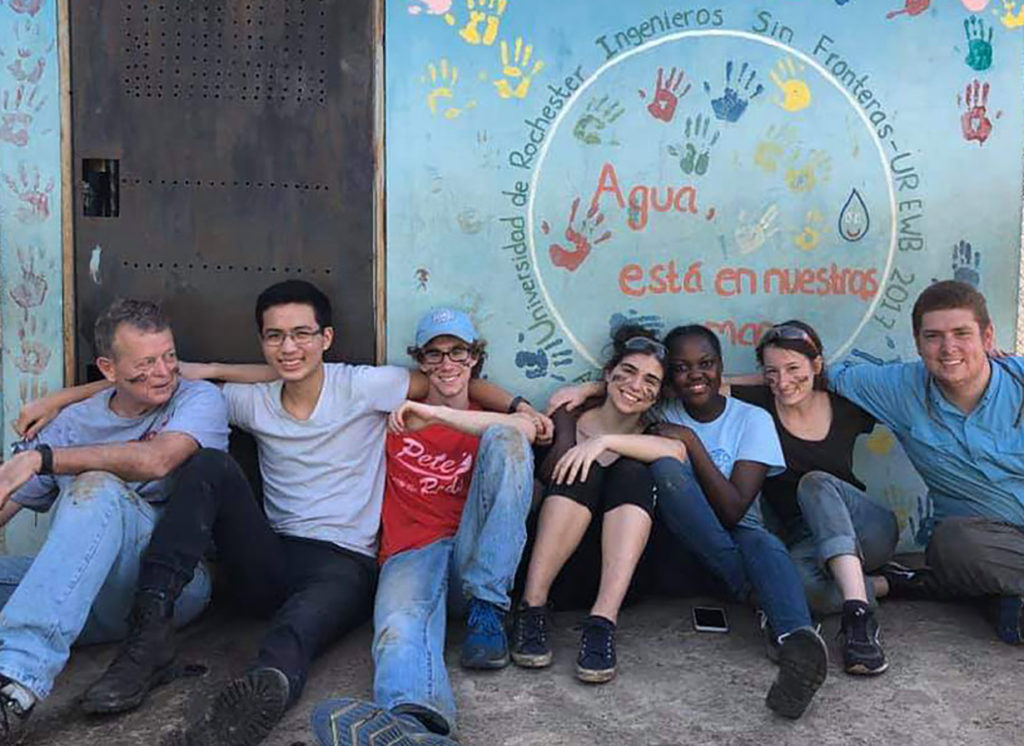 Members of the Engineers Without Borders team take a break in front of the blue shed that houses water disinfection system at Escuela Taller Santa Maria Josefa Rossello primary school in the Dominican Republic.