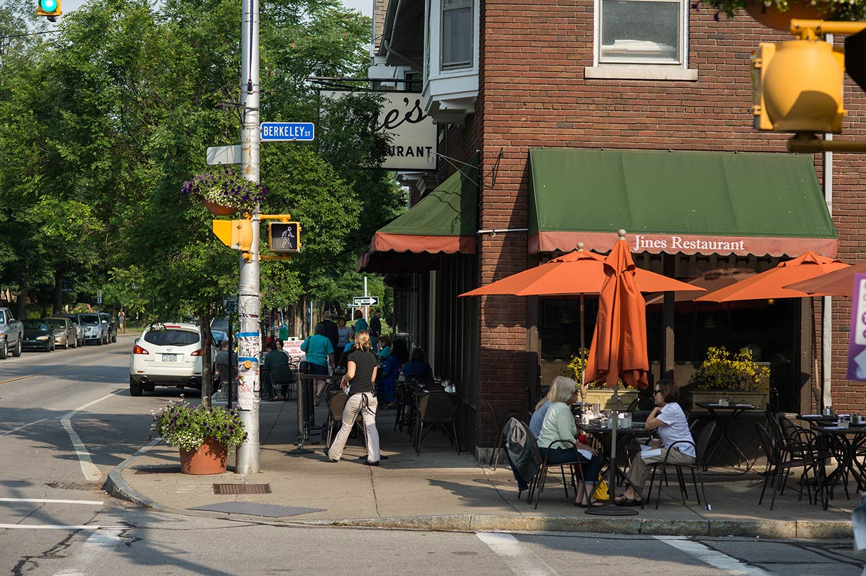 An exterior view of Jines restaurant with patrons eating at tables on the sidewalk.