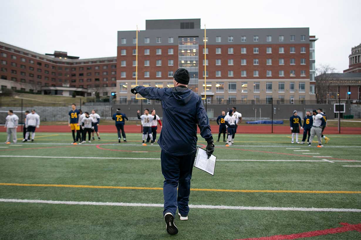 A football coach on field with players.