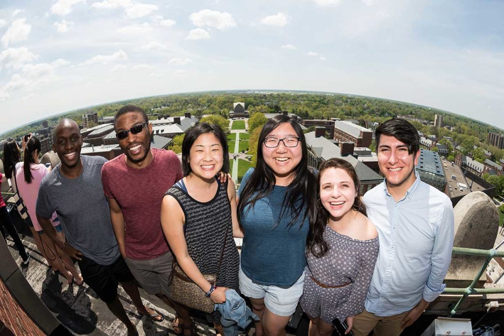 A group of students posing for the camera atop the tower of Rish Rhees Library.