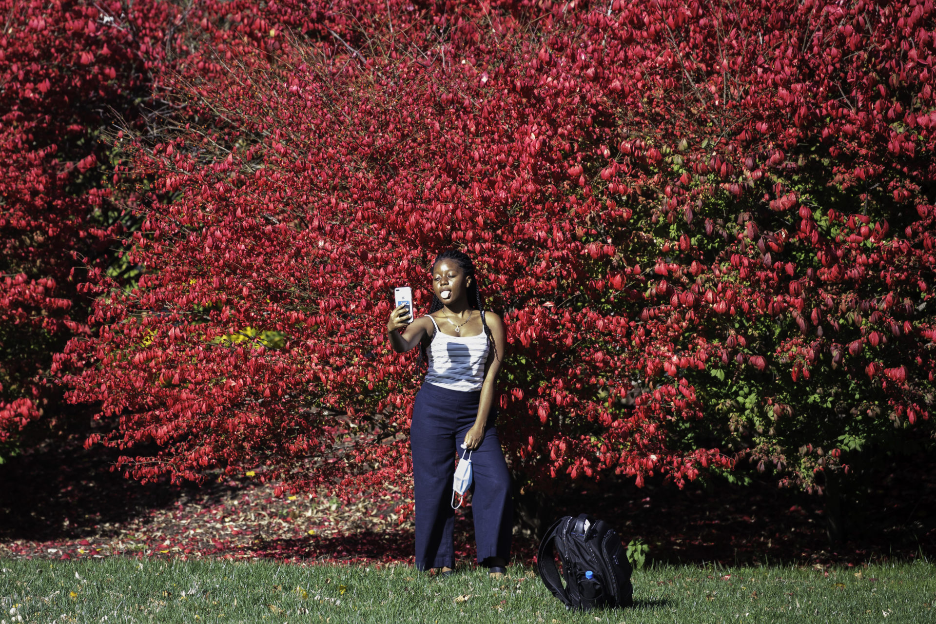 A student poses for a selfie as leaves change color.