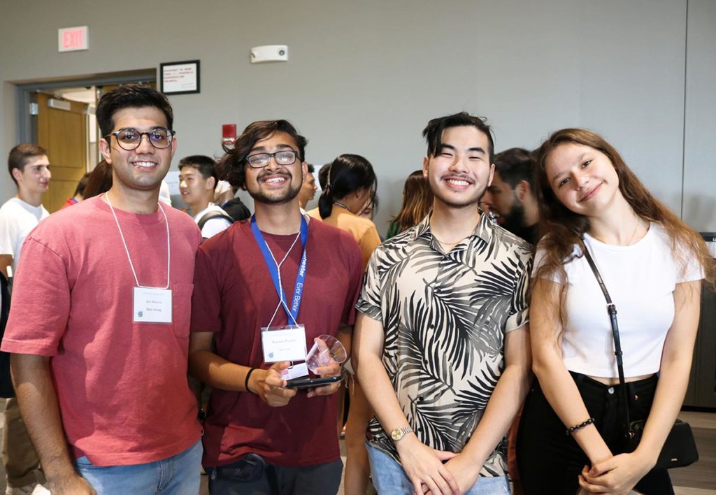 A group of four international students smiling at the camera.
