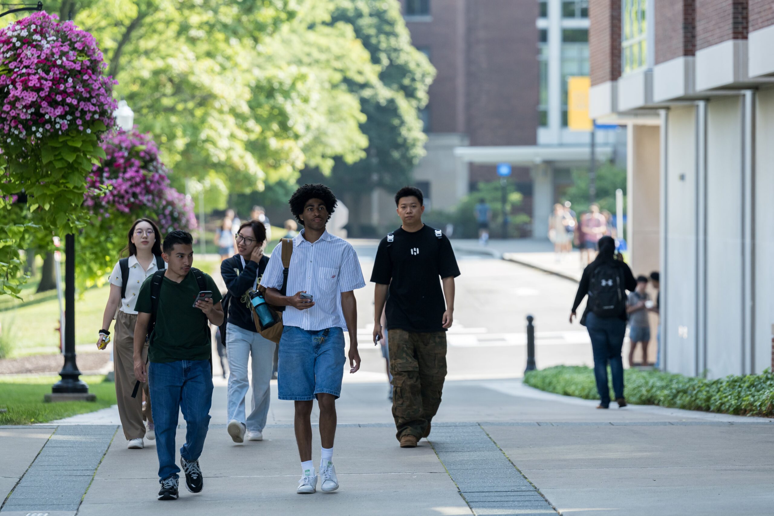 Multiple students walk past Wegmans Hall at the University of Rochester.