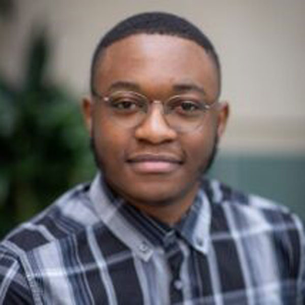 A University of Rochester student, Tamuda Chimhanda, wearing glasses and a plaid shirt.