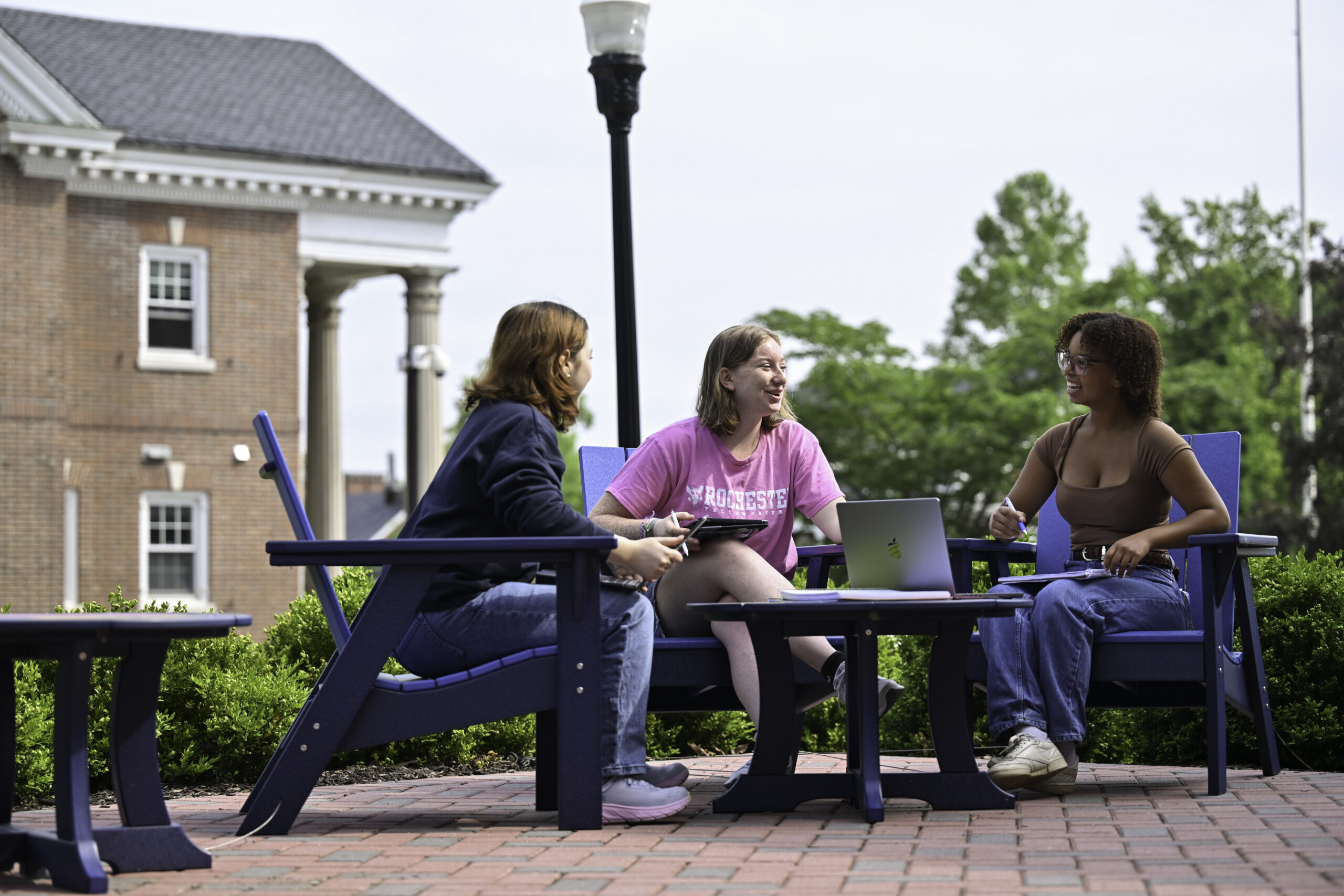 A group of students converse around a table outside Sloan Auditorium.